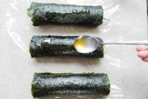 Korean rice roll kim bap recipe - add sesame oil on top of the wrapped rolls to make the surface shiny