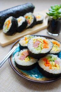 Korean rice roll kim bap recipe - now the kim bap rice roll were sliced and serve with orange carrot, green cucumber, yellow egg and pink luncheon wrapped with white rice and black seaweed. Yummy!