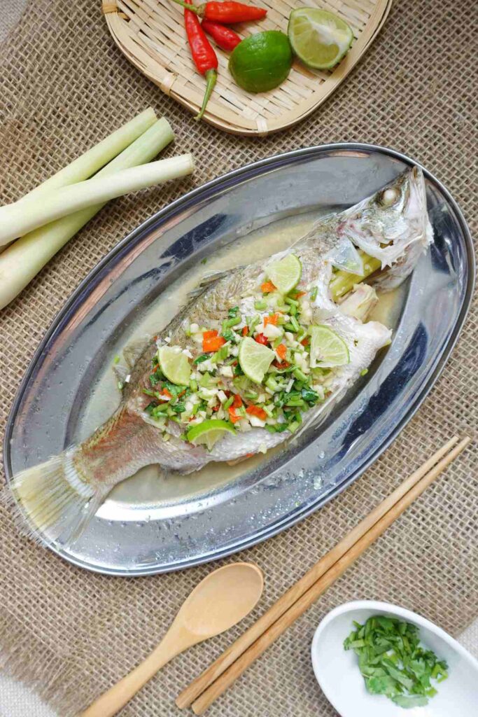 Thai-style steam fish recipe - Green lime and coriander, red chili and white garlic are mixed with fish sauce and laying on the steamed fish