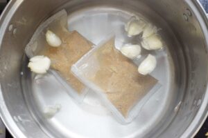 Bak kut teh soup packs and garlics boiled in a pot of boiling walter